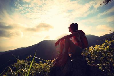 A young women sits in the mountains enjoying nature. 