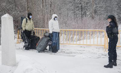 An RCMP officer stops people as they enter Canada via Roxham Road on the Canada-U.S. border in Hemmingford, Quebec, March 25, 2023. (THE CANADIAN PRESS/Graham Hughes)