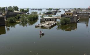 People use a makeshift raft to navigate floodwaters from monsoon rains, in the Dadu district of Sindh Province in Pakistan, on September 9, 2022. (AP Photo/Fareed Khan)