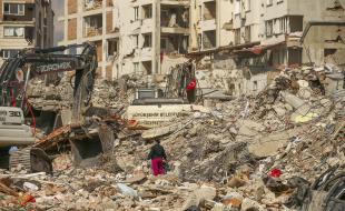 A man walks among debris as excavators demolish the remains of a destroyed building following the earthquake in Samandag, southern Turkey, on February 22, 2023. (AP Photo/Emrah Gurel) 