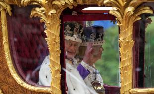 King Charles III waves from the carriage beside Queen Camilla during the royal procession following the King's coronation, in London on May 6, 2023. (THE CANADIAN PRESS/Nathan Denette)