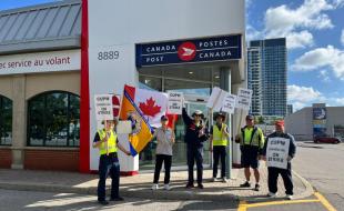 Canada Post workers picket outside a Canada Post outlet. (Photo via CUPW Local 602’s Facebook page.)